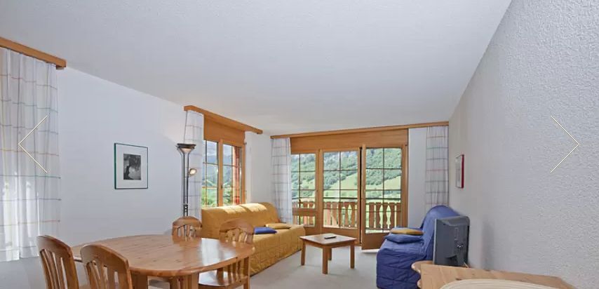 Living room with balcony doors and green mountain view